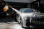 Foam cannon spraying thick snow foam on a black car