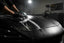 Professional detailer washing a matte black vinyl wrapped car with a soft microfiber mitt in a dark garage