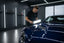 Professional detailer inspecting a flawless mirror-like paint finish with a Scangrip detailing light in a modern garage